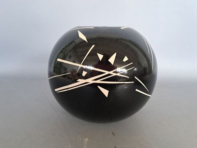 a black vase with white lines on it sitting on a table
