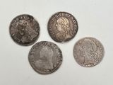quatre types différents de pièces d'argent sur une surface blanche