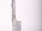 silver metal sculpture of a man sitting on a chair on a white background
