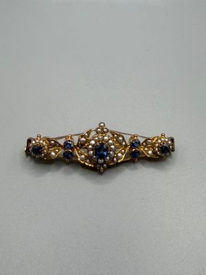 a close up of a gold brooch with blue and white stones