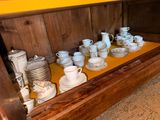 many cups and saucers sitting on a shelf in a room