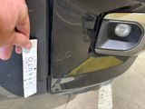 a person holding a sticker that is attached to the front of a car