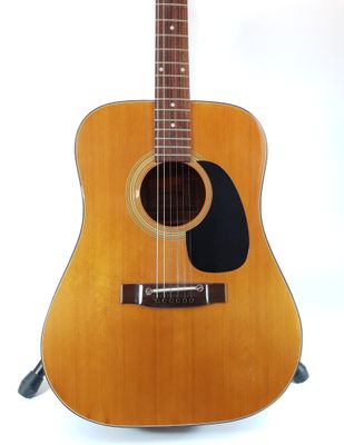 an acoustic guitar sitting on a stand against a white background