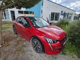 une voiture rouge garée devant un immeuble, à côté d'un arbre