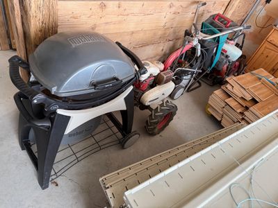 une photo d'un barbecue dans un garage, à côté d'un tas de bois