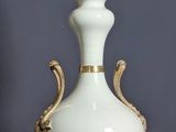 un vase blanc et doré surmonté d'une lampe
