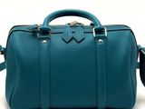 the teal colored bag is sitting on a white surface
