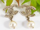 pair of chanel earrings with pearls and diamonds on a white surface