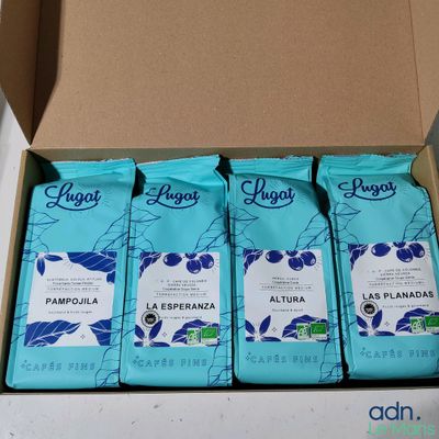 four bags of coffee sit in a cardboard box on a table