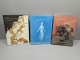 trois livres sont posés sur une table à fond blanc