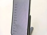 a cell phone with a broken screen sitting on a stand