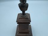 une image représentant la statue d'un homme coiffé d'un chapeau, posée sur un socle