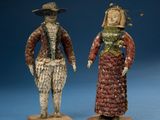 two figurines of a man and a woman dressed in period clothing