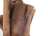 quelqu'un tient une paire de bottes marron ornées d'une étoile