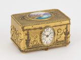 une boîte dorée ornée d'une horloge, posée sur une surface blanche