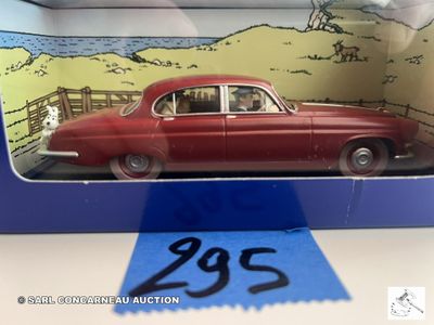 une image représentant une petite voiture rouge dans une boîte ornée d'un ruban bleu