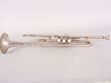 an old silver trumpet sitting on top of a white surface