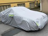 une voiture recouverte d'une housse grise dans la rue