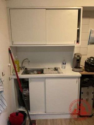 une petite cuisine avec des placards blancs et une serpillière rouge à l'intérieur