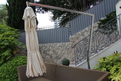 un canapé et un parasol sur une terrasse bordée d'un mur en pierre