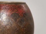 a brown vase with a red and black design on it
