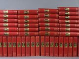 the red books are stacked on top of each other on a gray surface