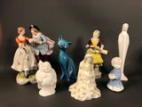 five figurines of people and a cat on a table