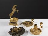 trois figurines en laiton posées sur une table blanche, sur fond noir