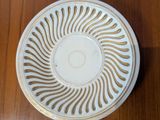 a white plate with a gold design on it on a wooden table