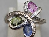 une photo en gros plan d'une bague ornée de trois pierres de couleurs différentes