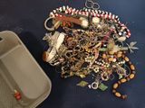 a tray of jewelry on the floor next to a container of beads