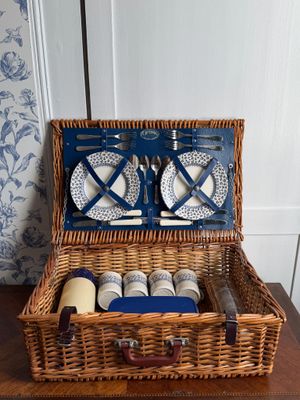 un panier de pique-nique en osier contenant des assiettes et des tasses