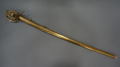 an old gold sword with a metal handle on a white surface