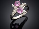 une bague sertie d'un saphir rose et de diamants, posée sur un fond noir