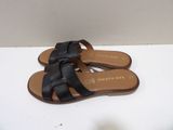 black leather sandals with cross straps on top of a white surface