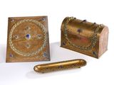 une boîte dorée ornée de pierres bleues, à côté d'une boîte contenant un stylo
