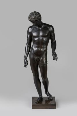 a bronze statue of a man standing on a wooden base
