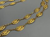 two long gold necklaces on a gray surface with a black background