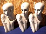 trois têtes de mannequins posées sur une table bleue