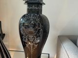 a black vase sitting on a glass table next to a book