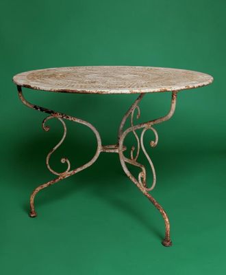 an old iron table with a marble top on a green background