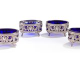 trois bols en verre argenté et bleu posés sur des socles, disposés sur une surface blanche
