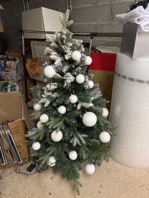 un petit sapin de Noël décoré de boules blanches et recouvert de neige