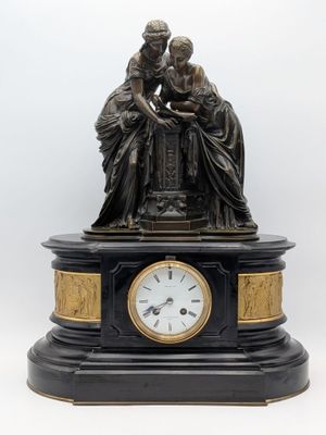 une statue représentant deux femmes assises sur une table, avec une horloge devant elles