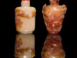 pair of chinese carved glass snuff bottles on a reflective surface