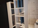 a tall white bookcase in the corner of a room