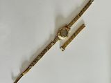 an image of a gold watch and a pen on a white surface