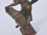 bronze statue of a woman holding a book on a wooden base