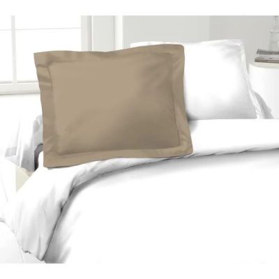 un gros plan sur un oreiller posé sur un lit aux draps blancs