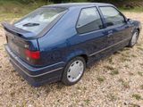 a picture of a blue car parked in a gravel lot